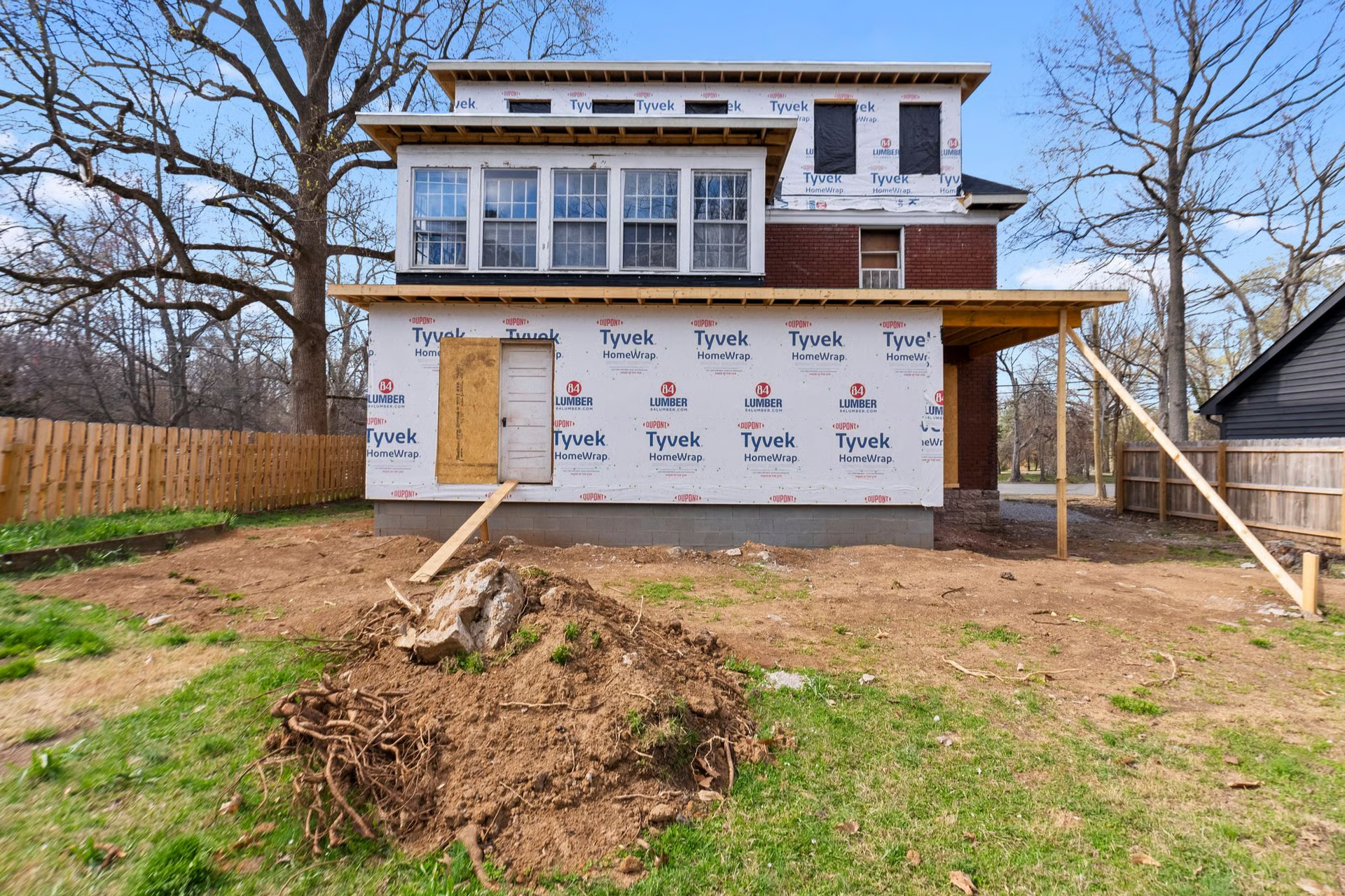 House under construction; exterior view with wood framing, unfinished siding, and open land.