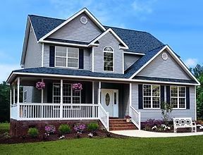 Two-story house with gray siding, blue roof, white porch, and landscaping.