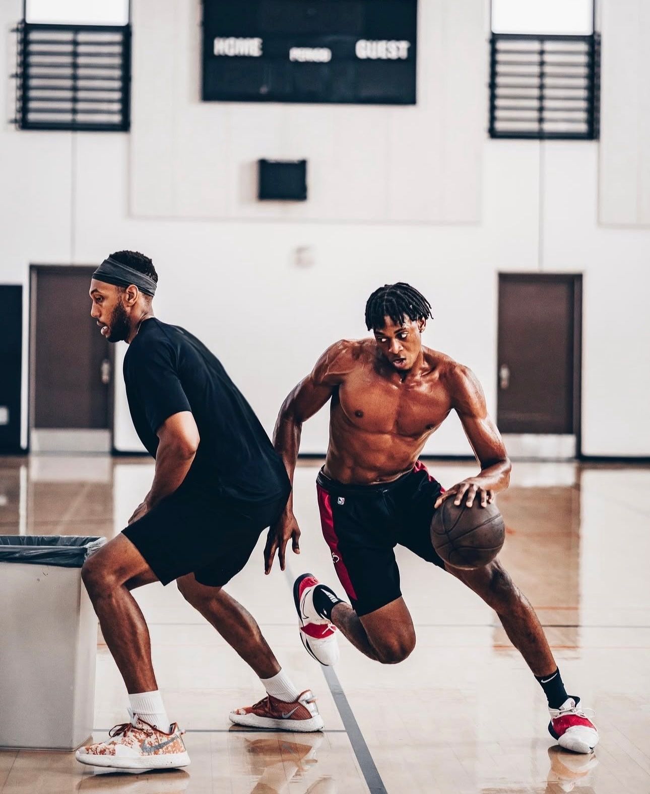 Two men are playing basketball on a court without shirts.