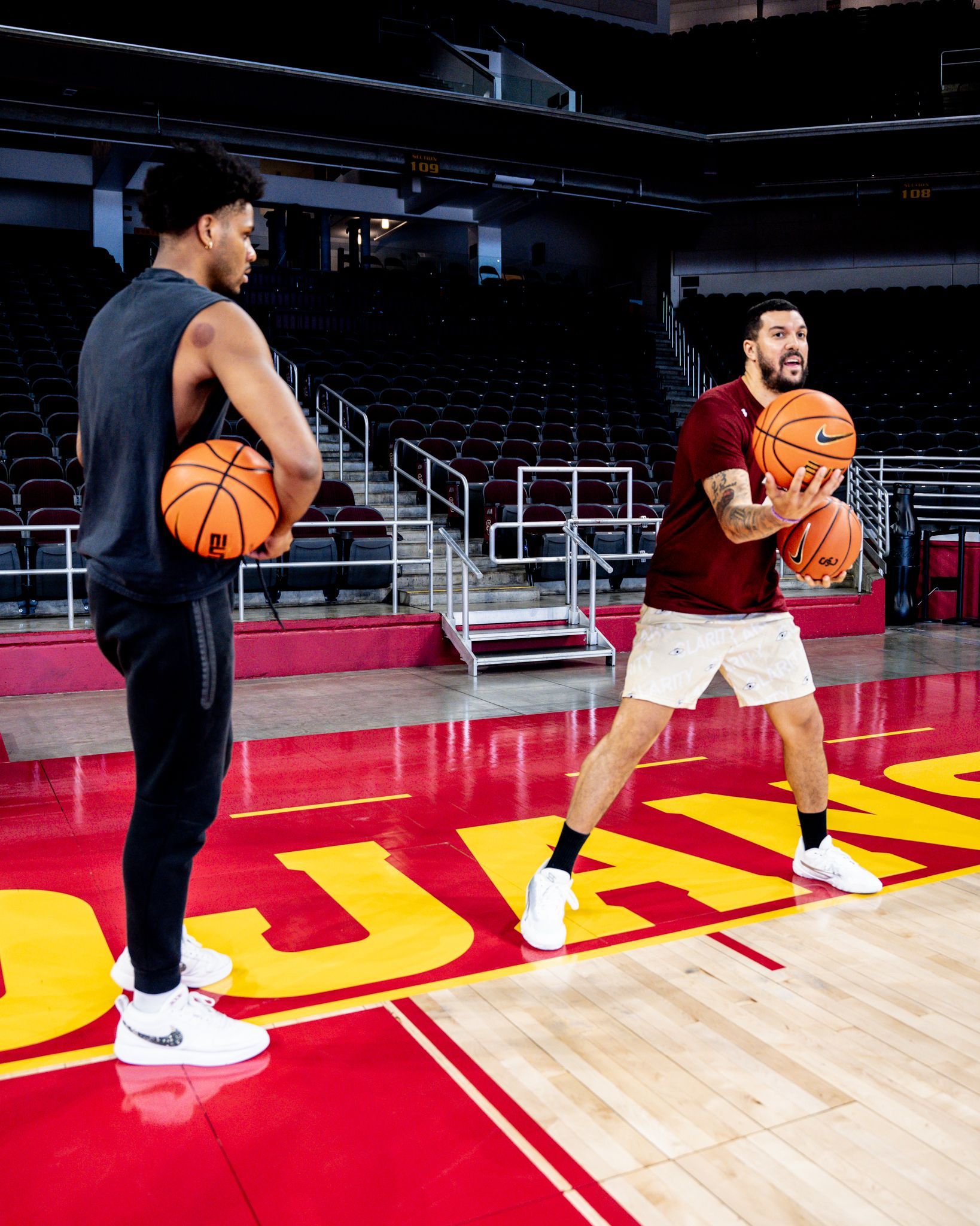 Two men are holding basketballs on a basketball court.
