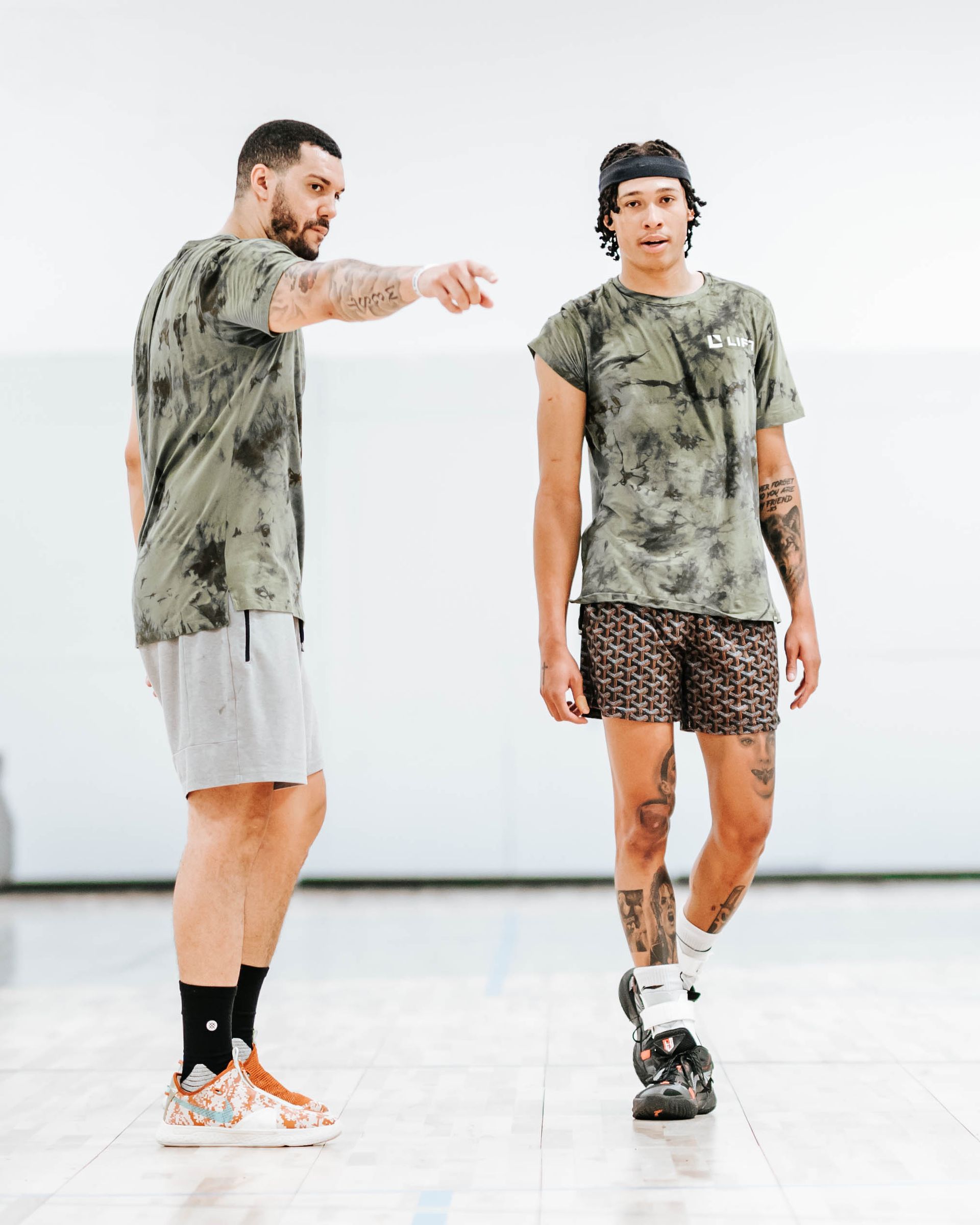 Two men are standing next to each other on a basketball court.