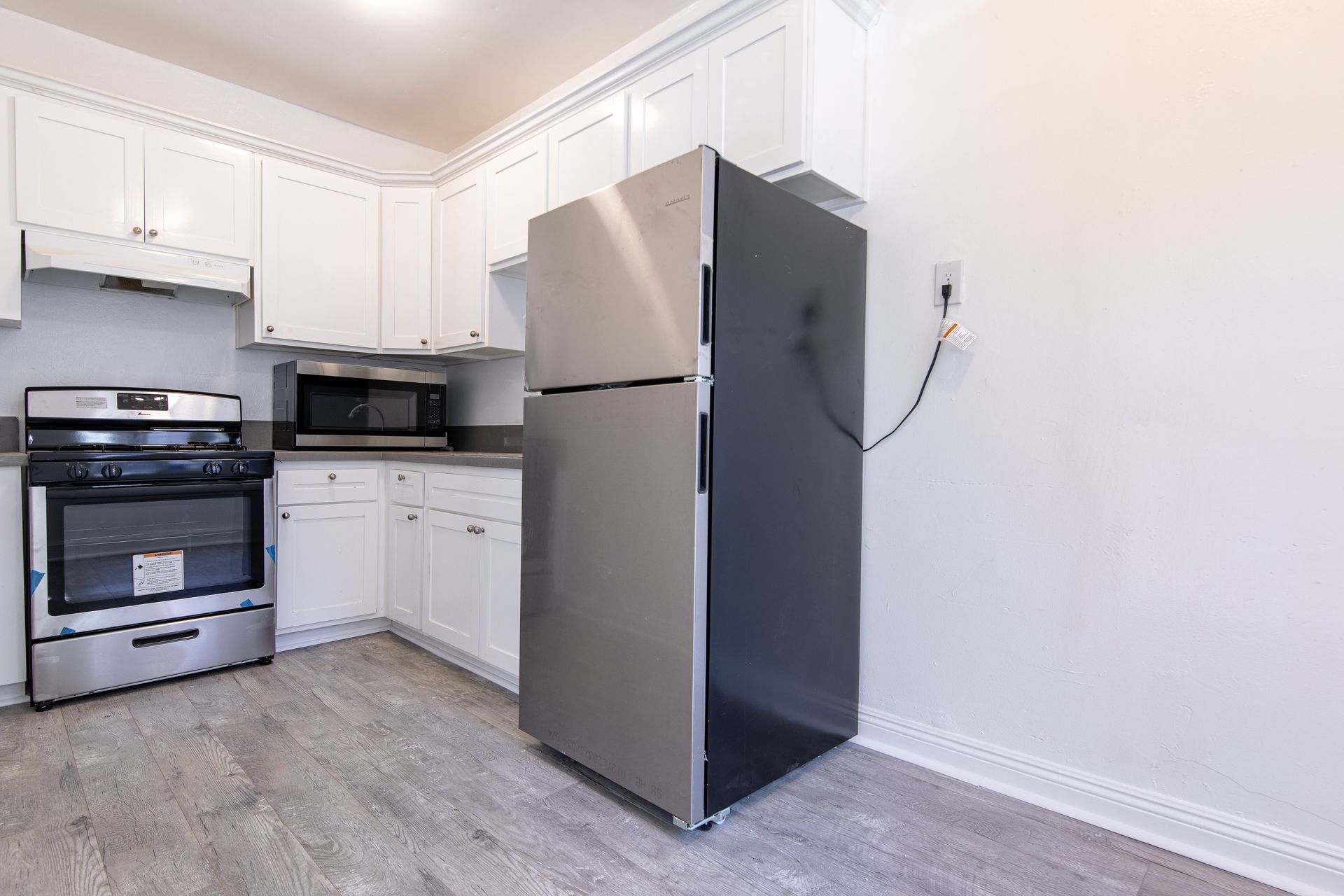 Kitchen with white cabinets, stainless steel appliances, and gray flooring.