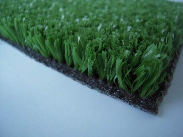 Primo piano di un campione di erba sintetica verde che mostra le fibre e il supporto nero testurizzato.