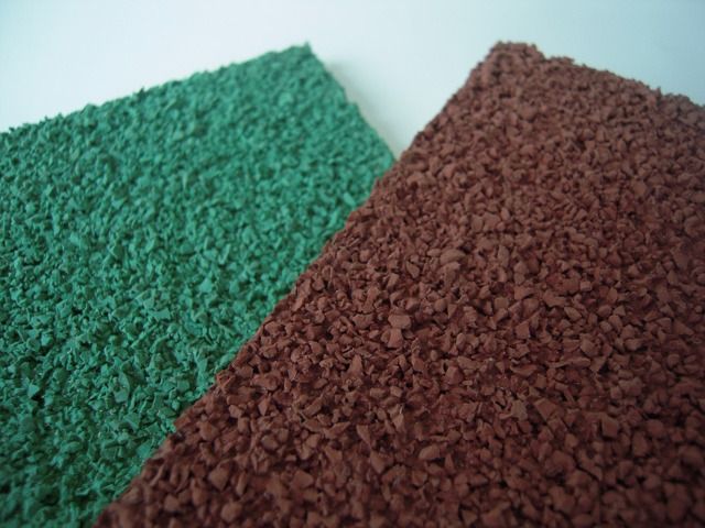 Due lastre di pavimentazione in gomma EPDM testurizzata, una verde e una marrone rossastra, posizionate in diagonale.