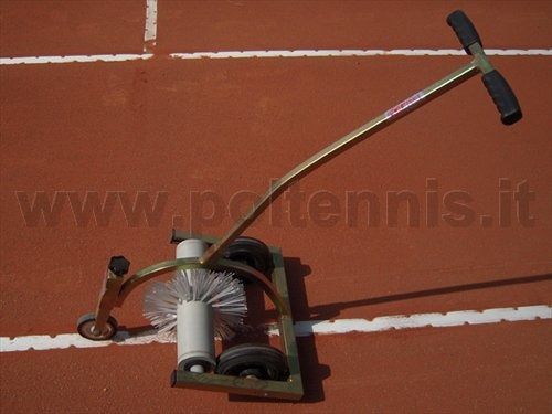 Uno strumento per tracciare le linee con spazzola rotante e manico, mostrato su un campo da tennis in terra battuta rossa.