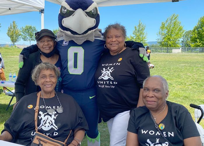 A group of women are posing for a picture with a mascot.