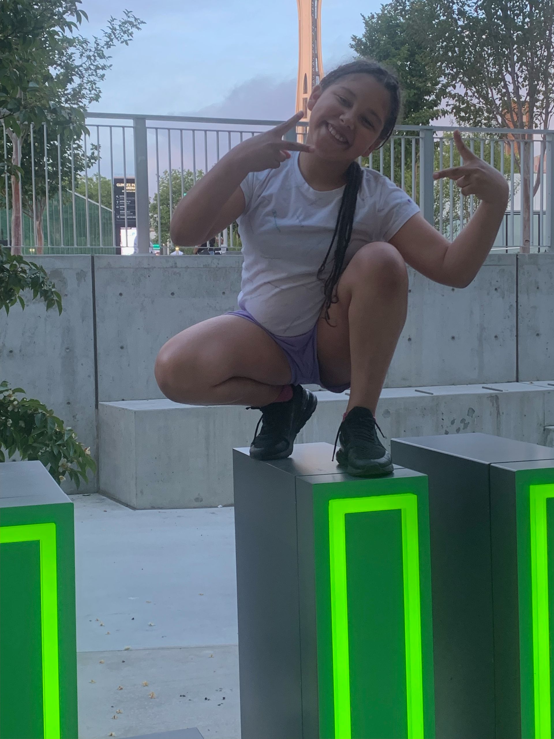 A young girl is squatting down on a green block