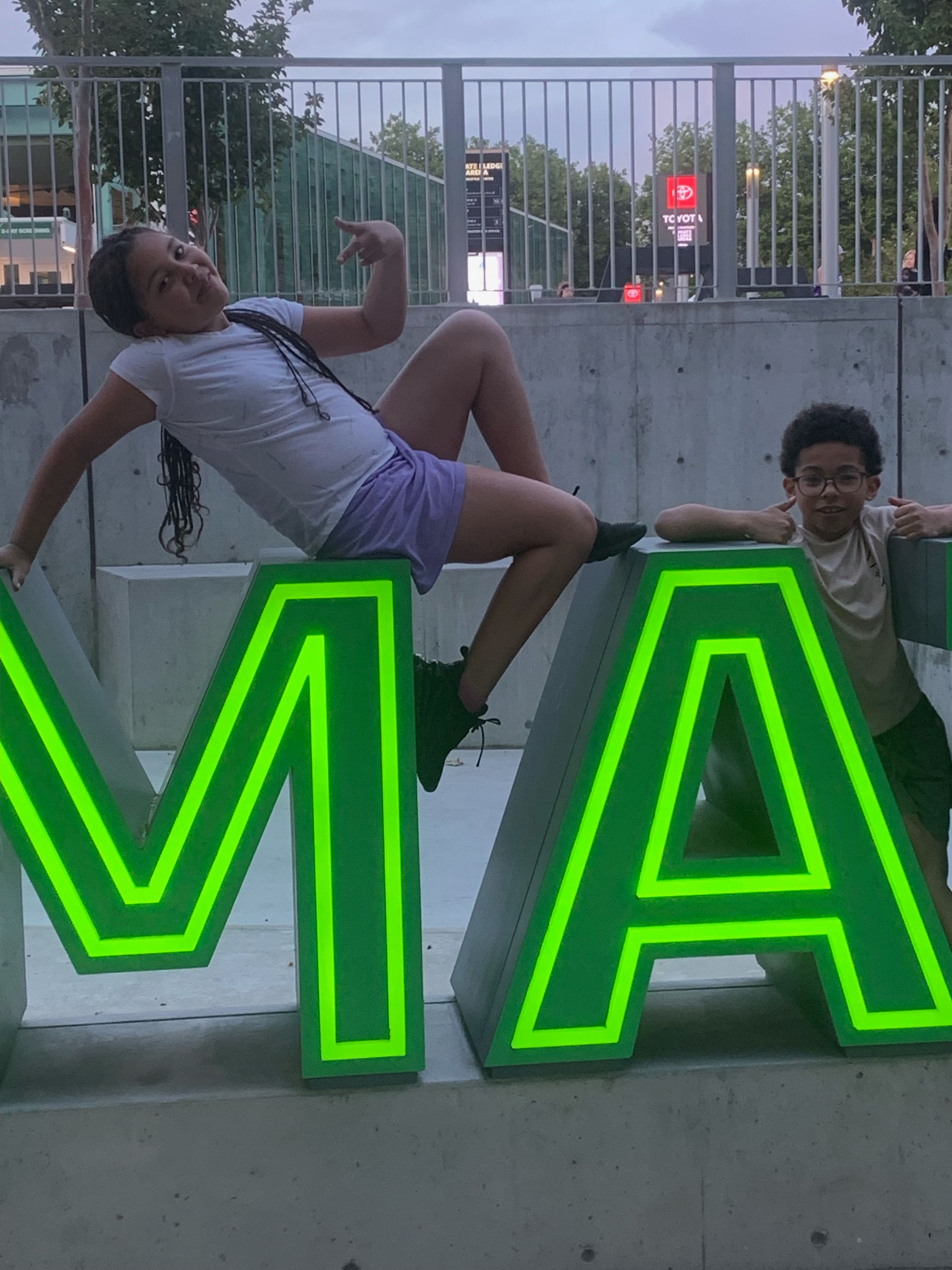 A girl and a boy are posing for a picture in front of a sign that says ma