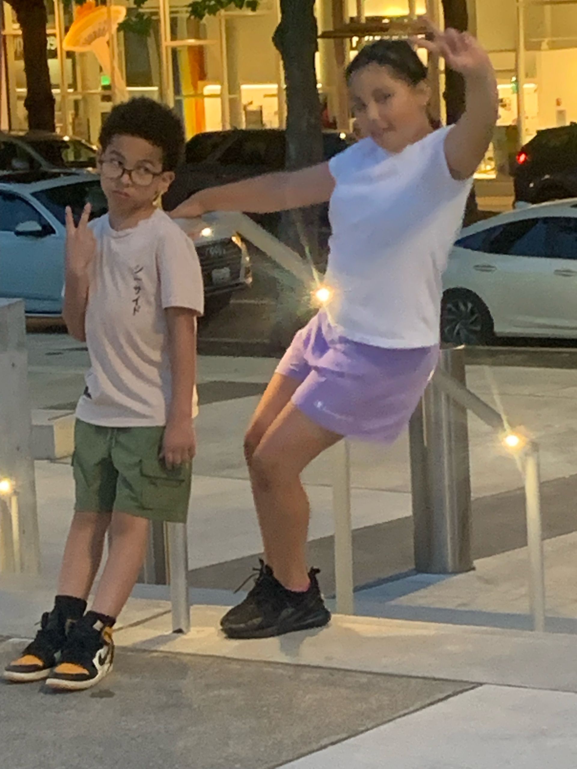 A boy and a girl are standing next to each other on a sidewalk