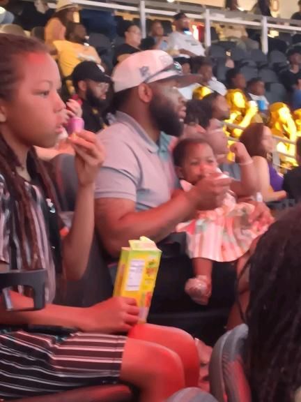 A group of people sitting in a stadium eating popcorn