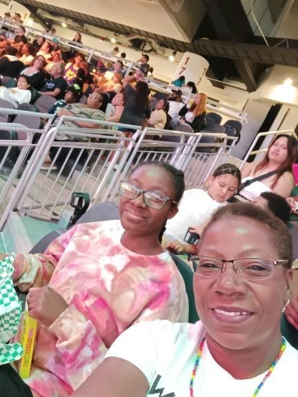 Two women wearing glasses are sitting in a crowded stadium