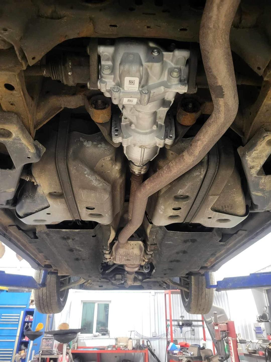 The underside of a car is shown in a garage.