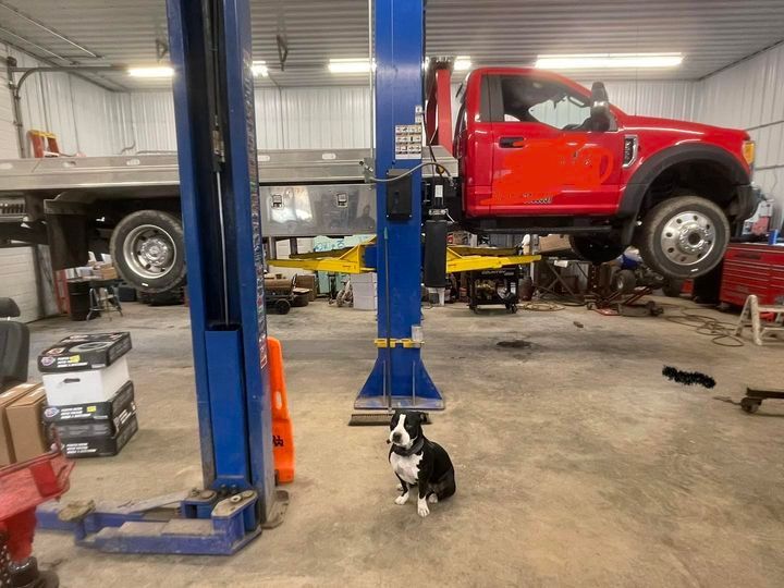 A red truck is sitting on a lift in a garage.
