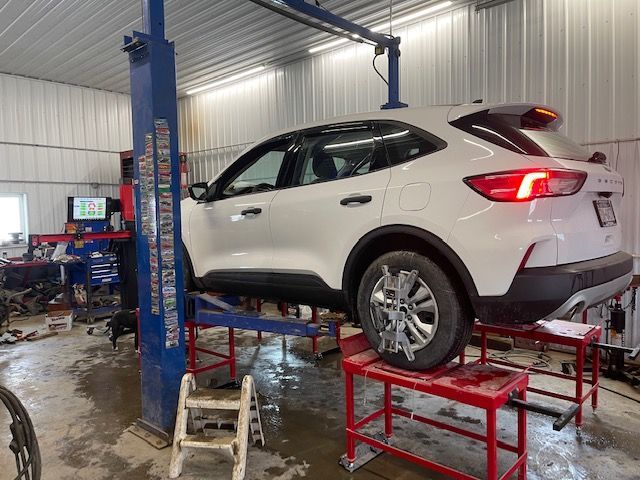 A white car is sitting on a lift in a garage.