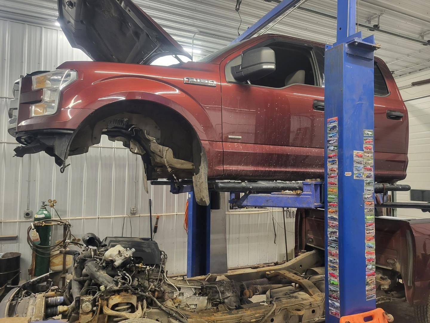 A red truck is sitting on top of a blue lift in a garage.