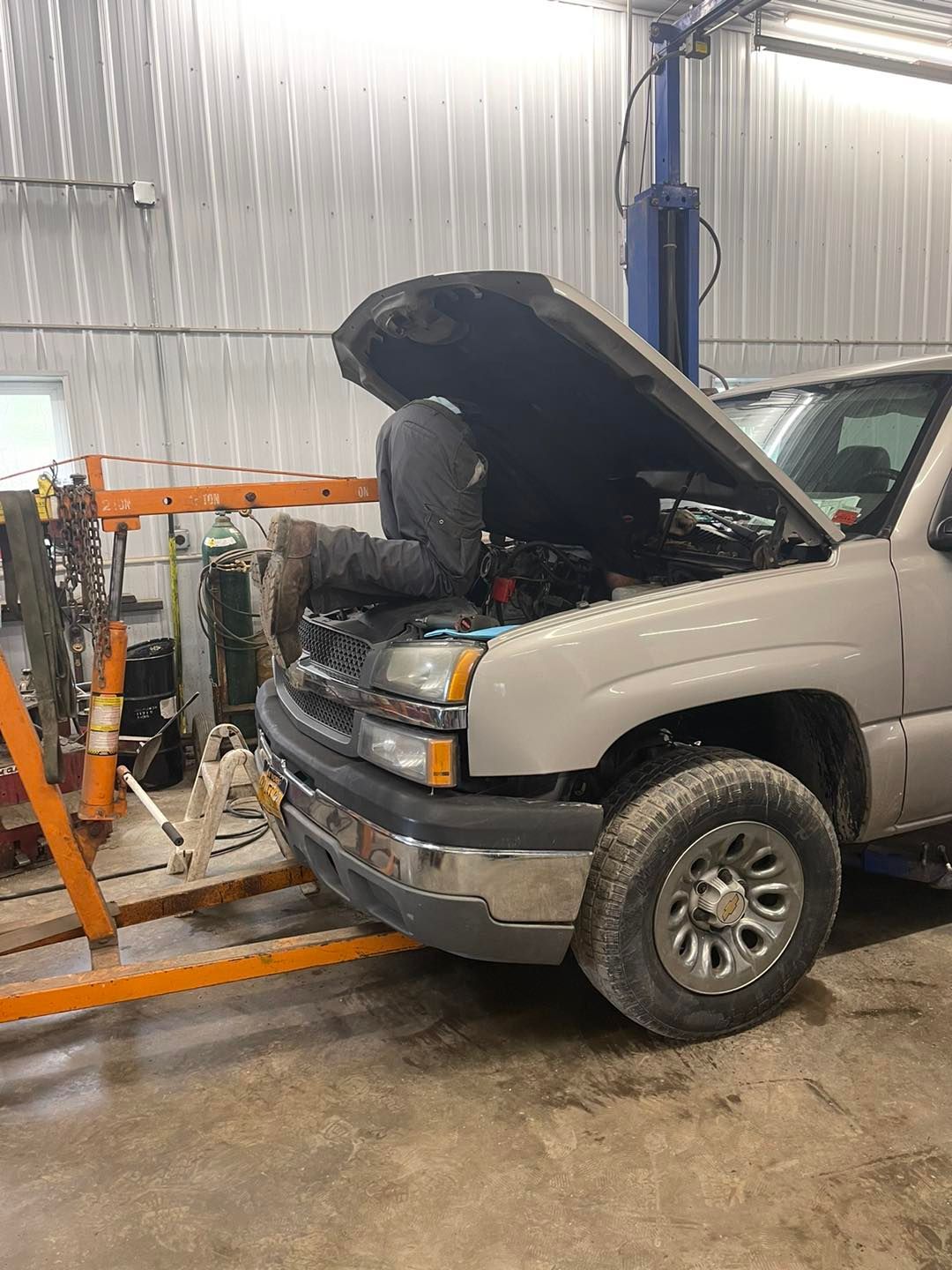 A man is working on the engine of a truck in a garage.