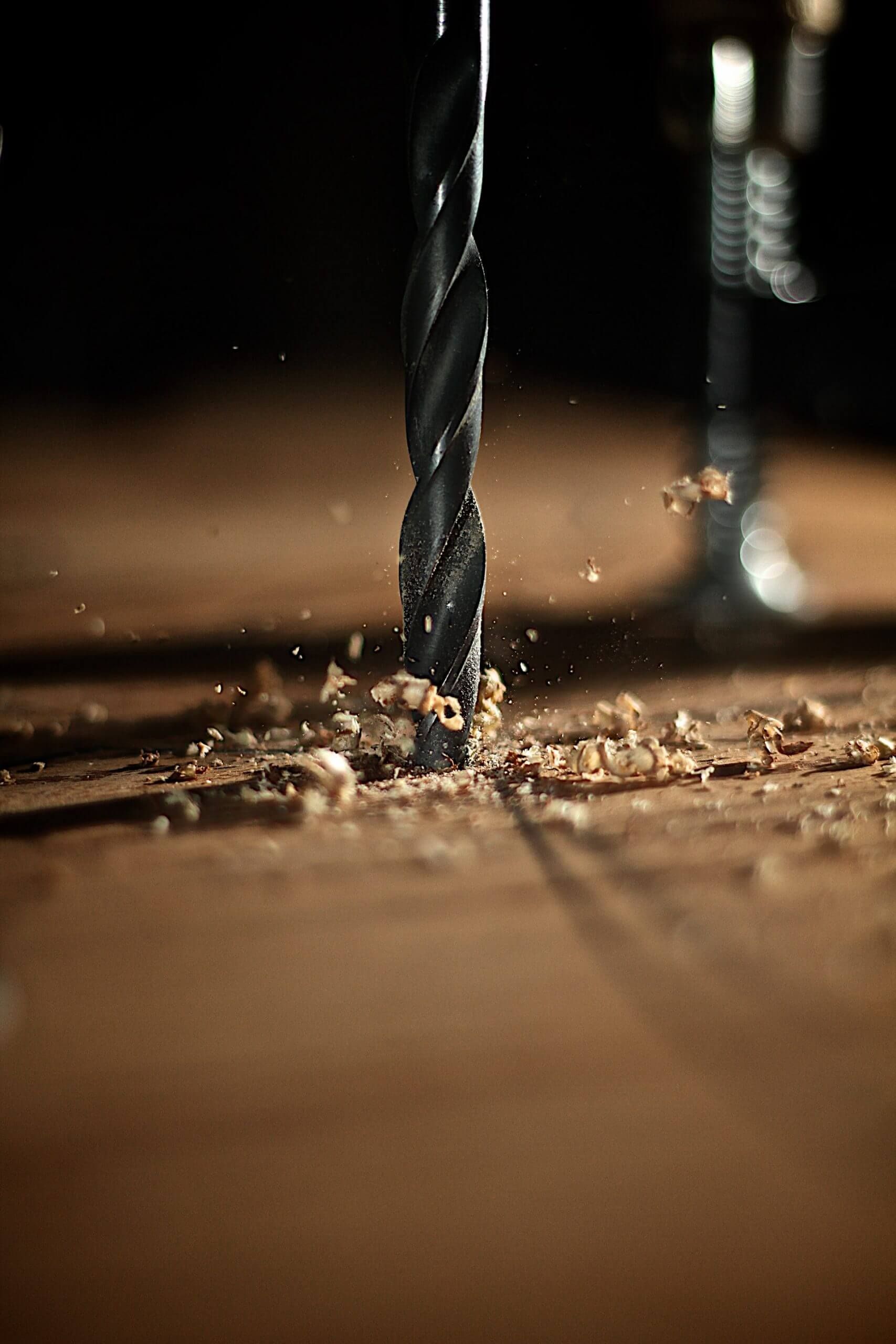 A close up of a drill bit cutting a hole in a piece of wood.