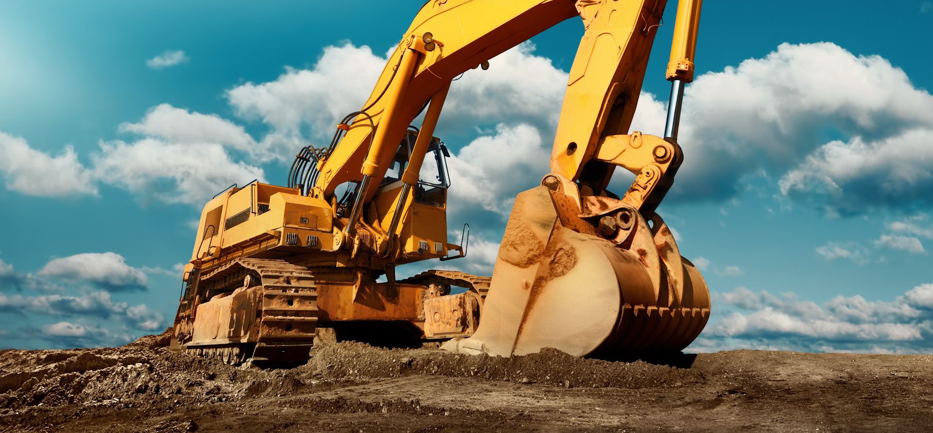 A yellow excavator is digging a hole in the dirt on a construction site.