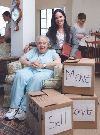 Marty Stevens-Heebner sits next to an elderly woman surrounded by moving boxes