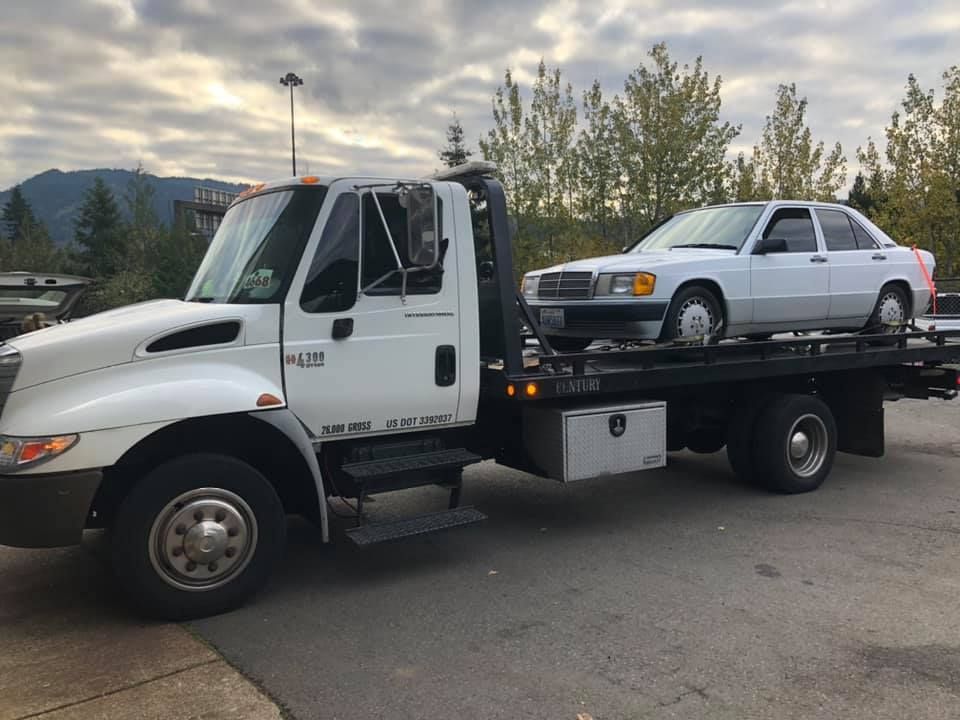 A tow truck with a car on the back of it.