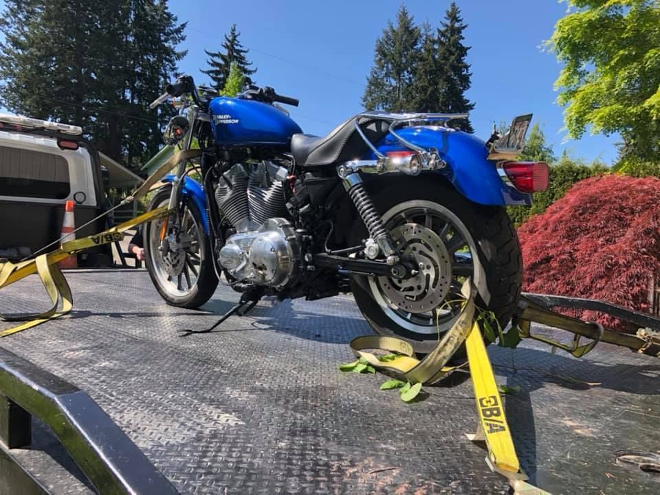 A blue motorcycle is sitting on top of a tow truck.