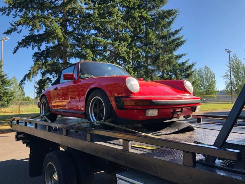 A red porsche is sitting on top of a tow truck.