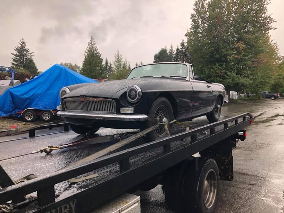 A black car is being towed by a tow truck.