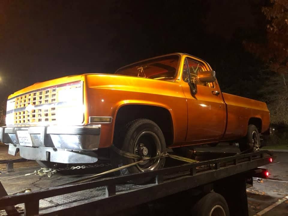 An orange truck is sitting on top of a tow truck.