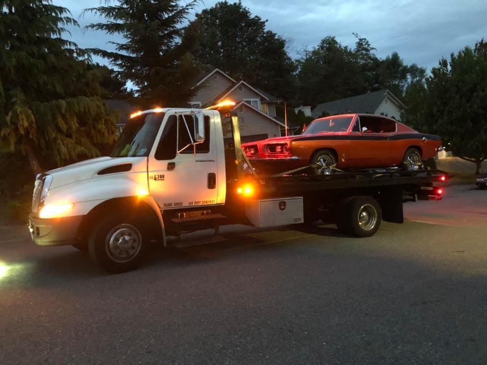 A white tow truck is carrying a red car