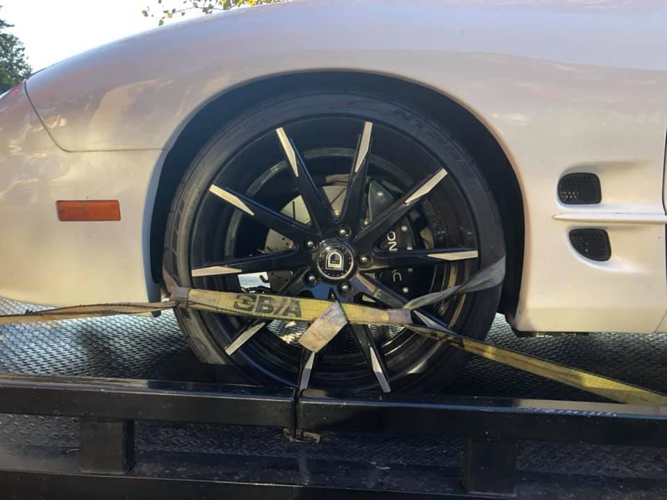 A white car is being towed by a tow truck