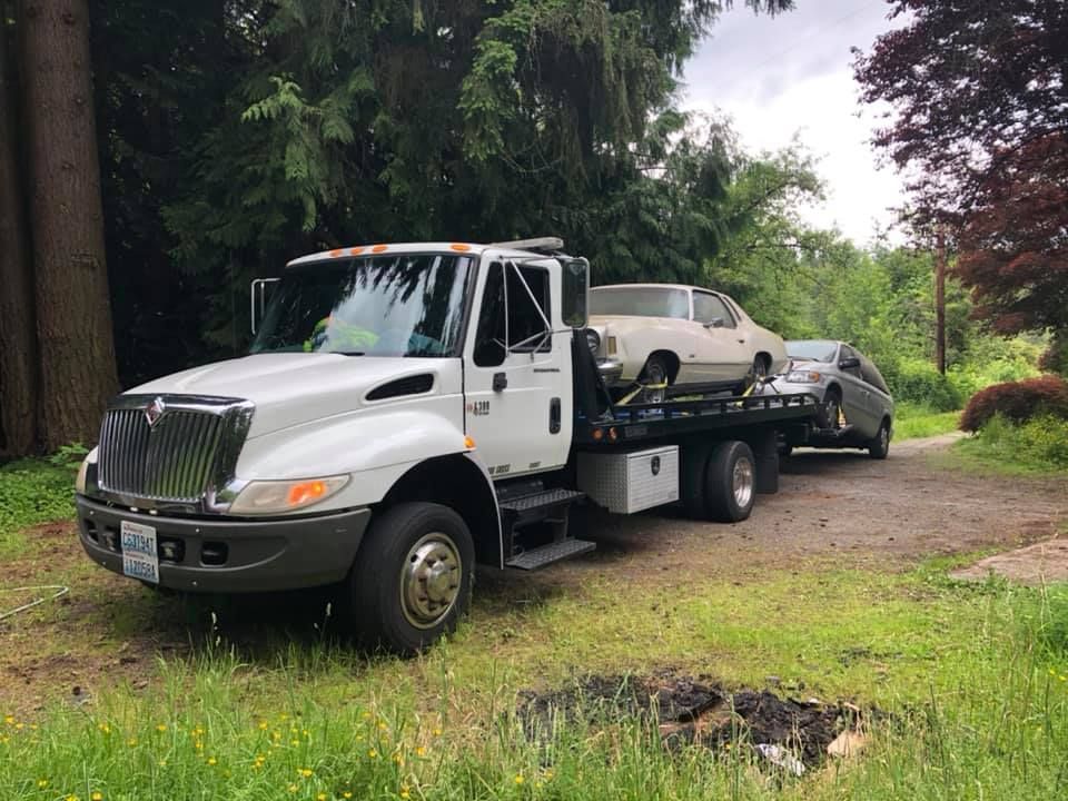 A tow truck is towing a car in a grassy field.