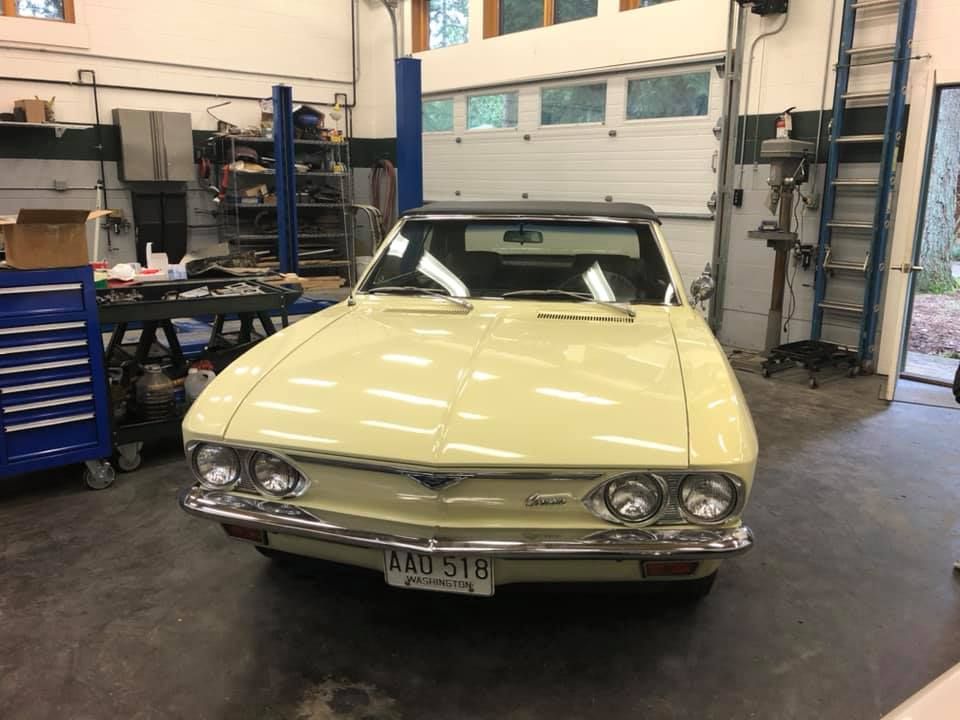 A yellow car is parked in a garage next to a garage door.
