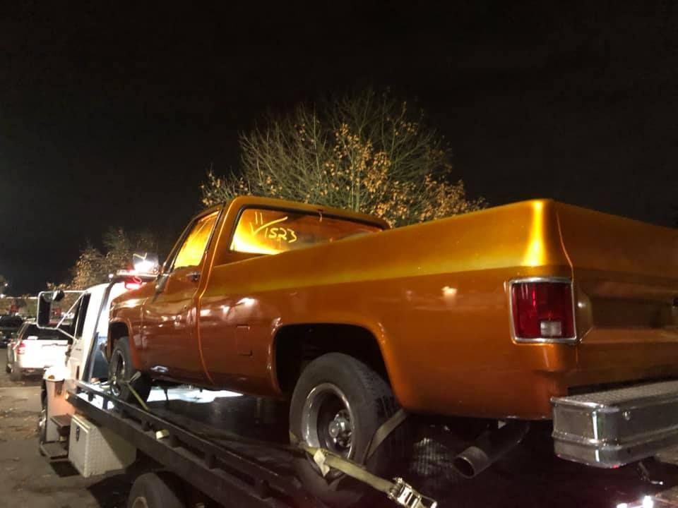 A truck is being towed by a tow truck at night