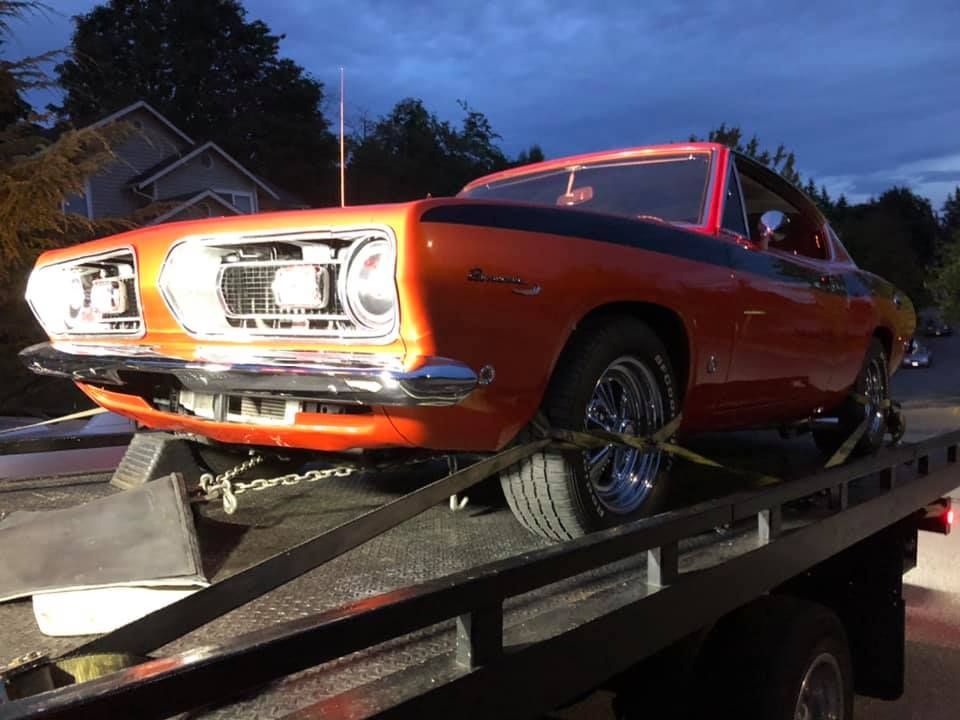 An orange car is sitting on top of a tow truck.