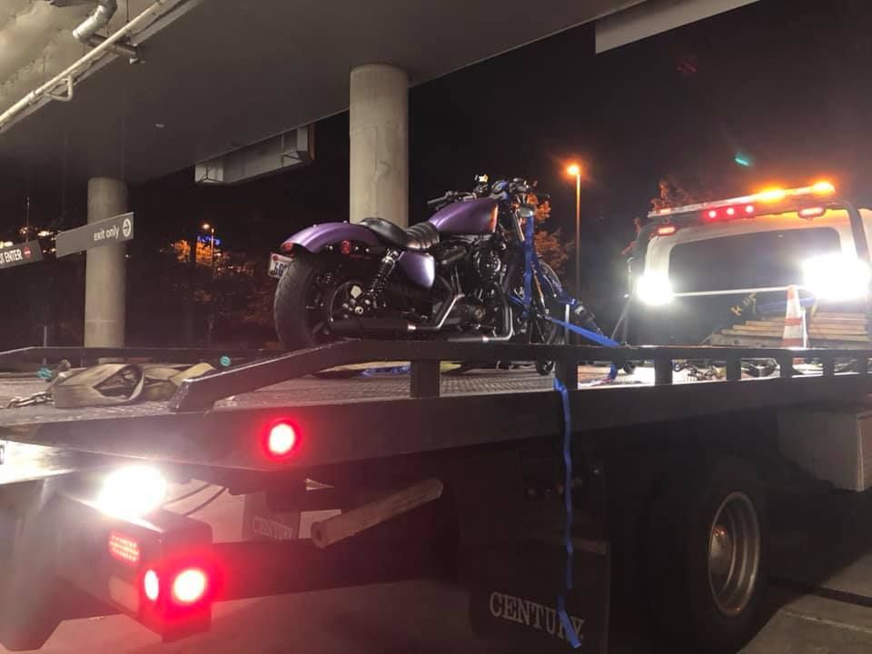 A purple motorcycle is sitting on top of a tow truck.