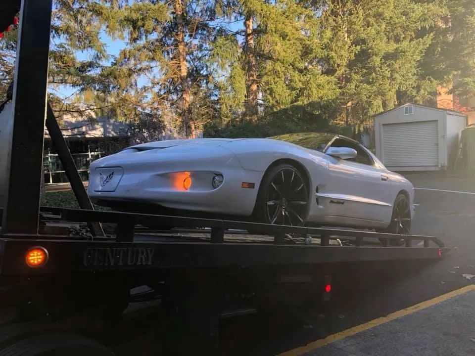 White Pontiac Firebird Trans Am on a tow truck, rear view.
