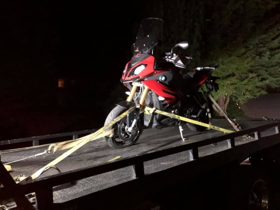 A motorcycle is being towed by a tow truck at night