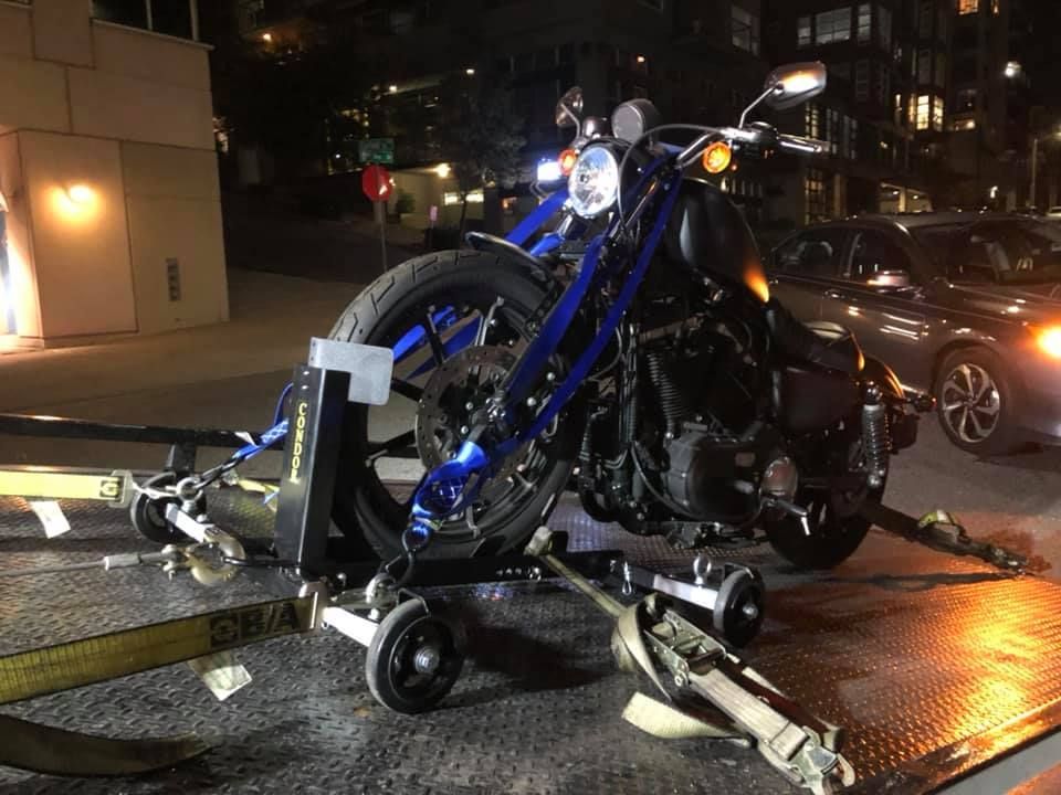 A motorcycle is being towed by a tow truck at night.