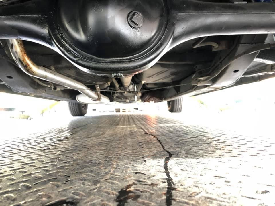 A close up of the underside of a car on a road.