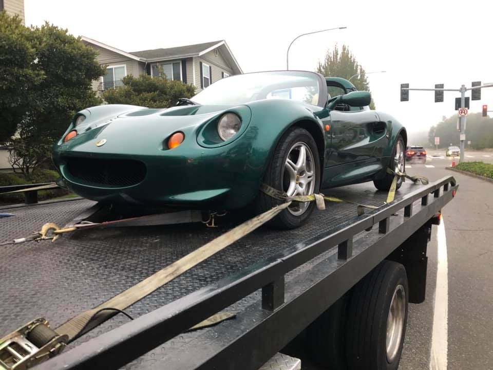 A green sports car is being towed by a tow truck