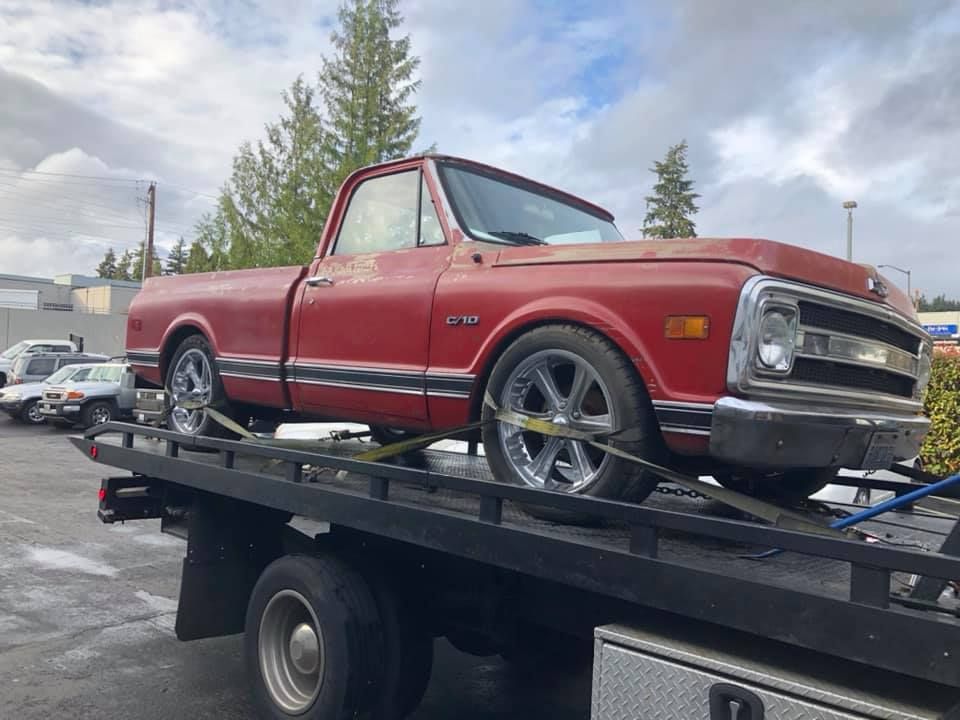 A red truck is sitting on top of a tow truck.
