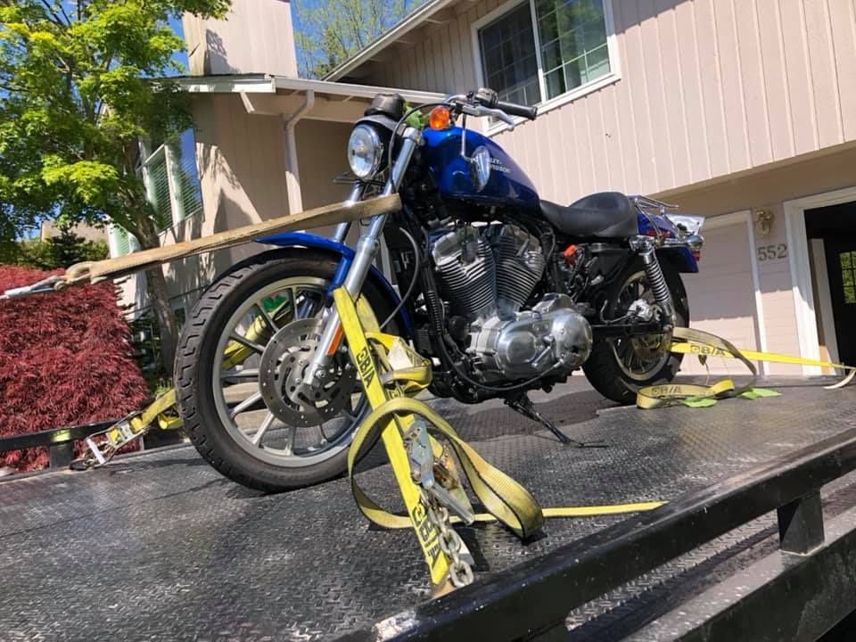 A blue motorcycle is sitting on top of a tow truck.