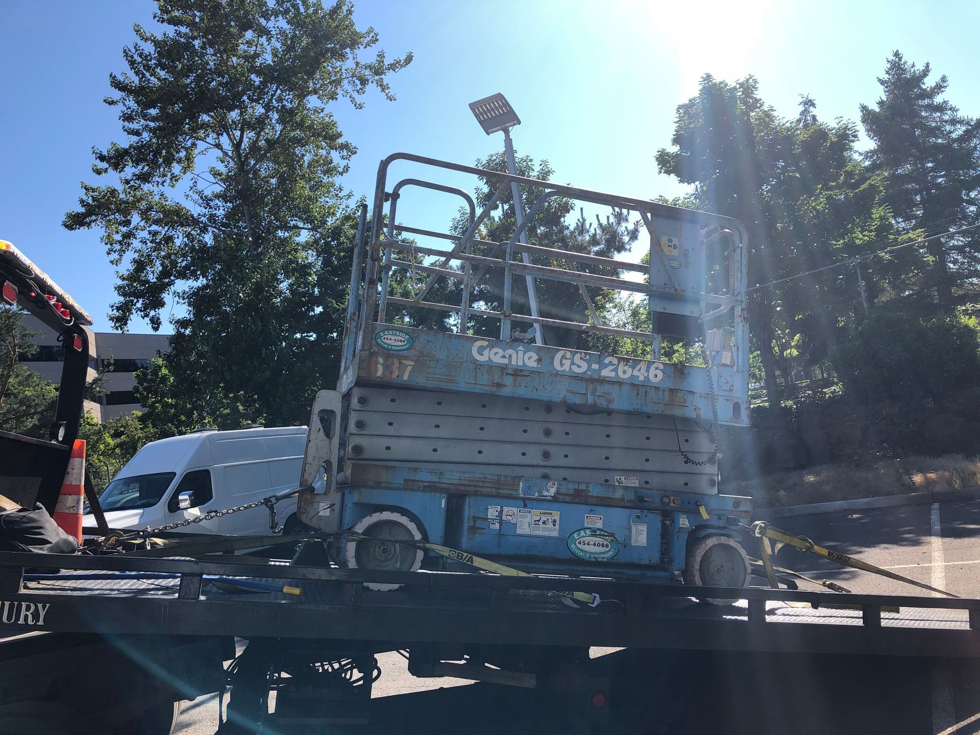 A genie scissor lift is sitting on top of a tow truck
