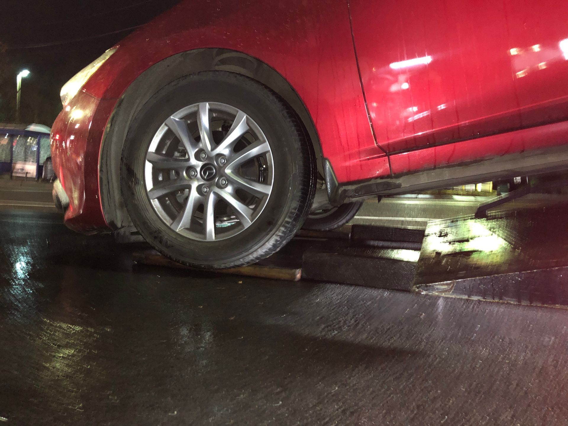 A red car is being towed by a tow truck