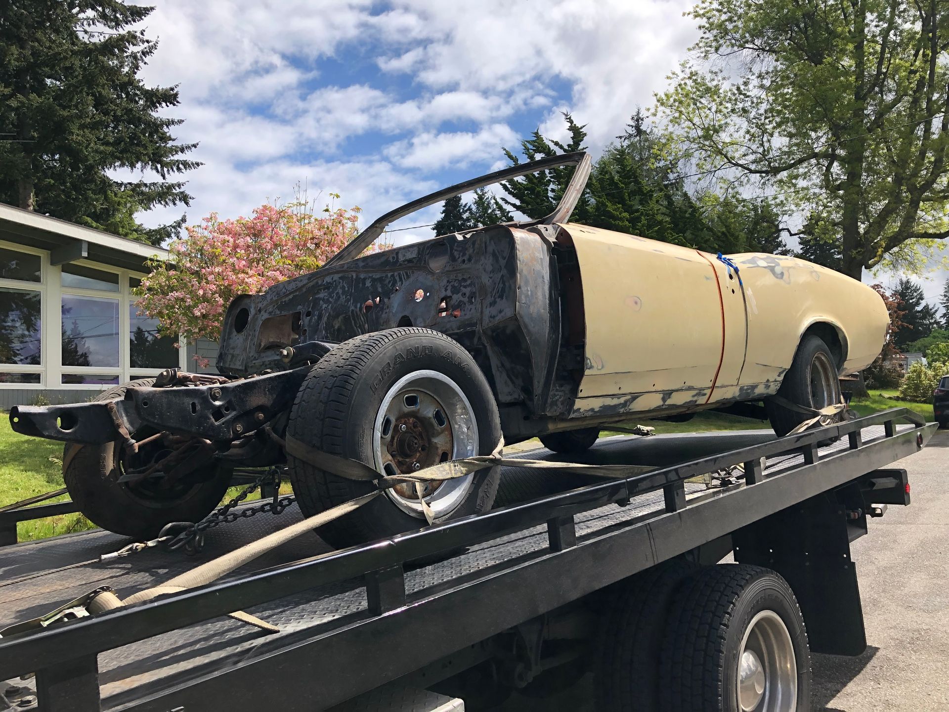 A yellow car is sitting on top of a tow truck.