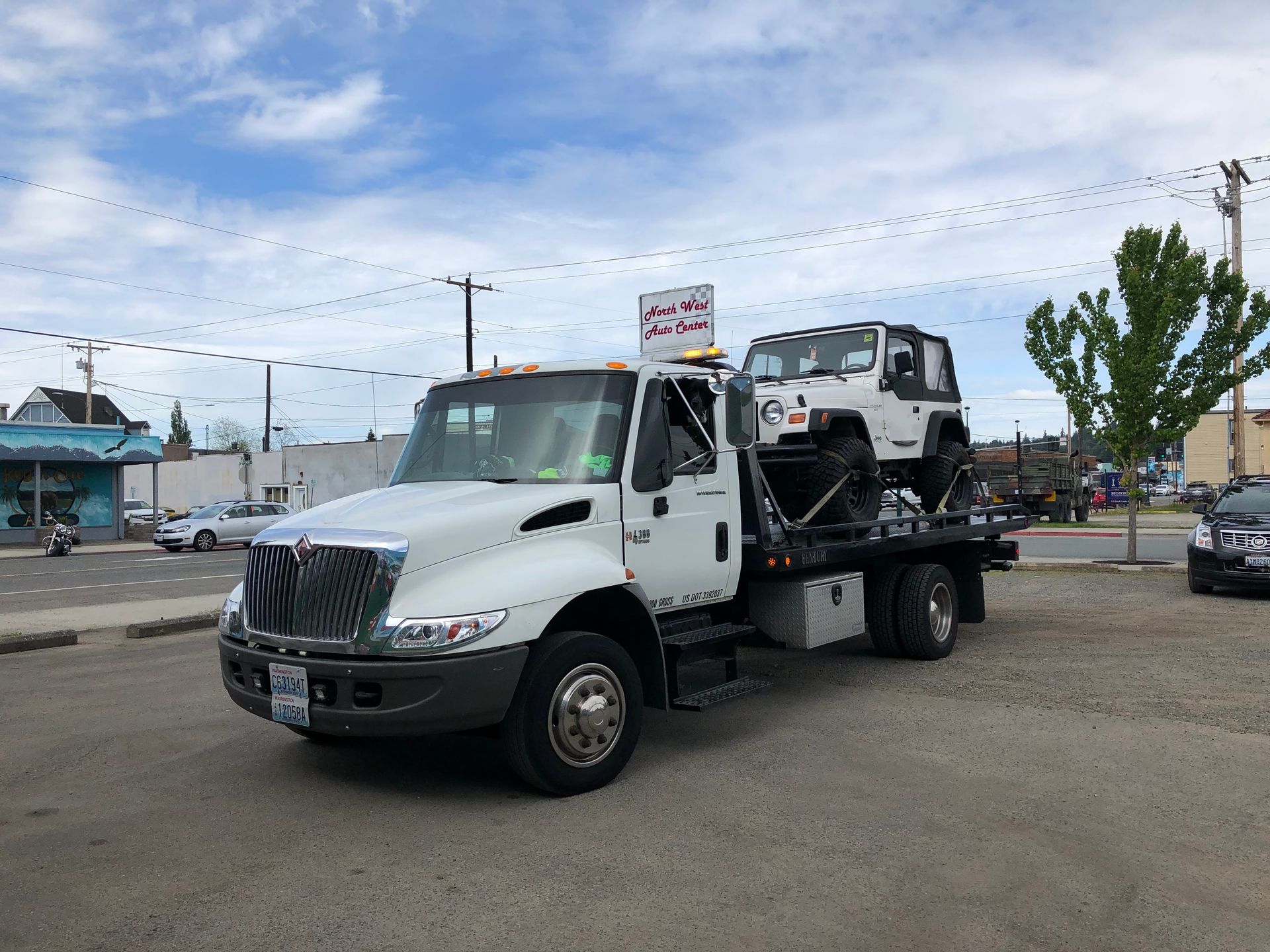A tow truck is carrying a jeep on the back of it.