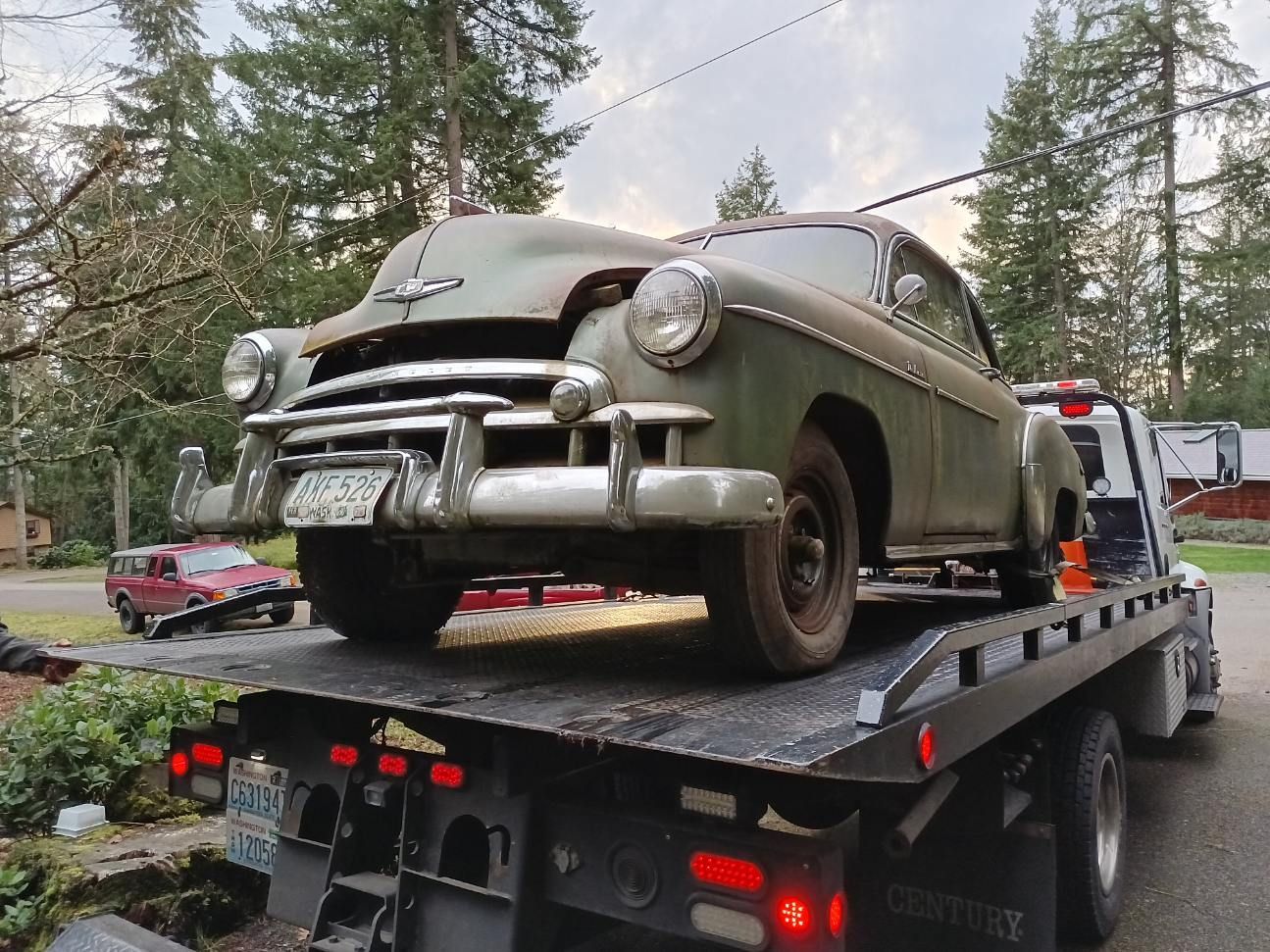 An old car is sitting on top of a tow truck.