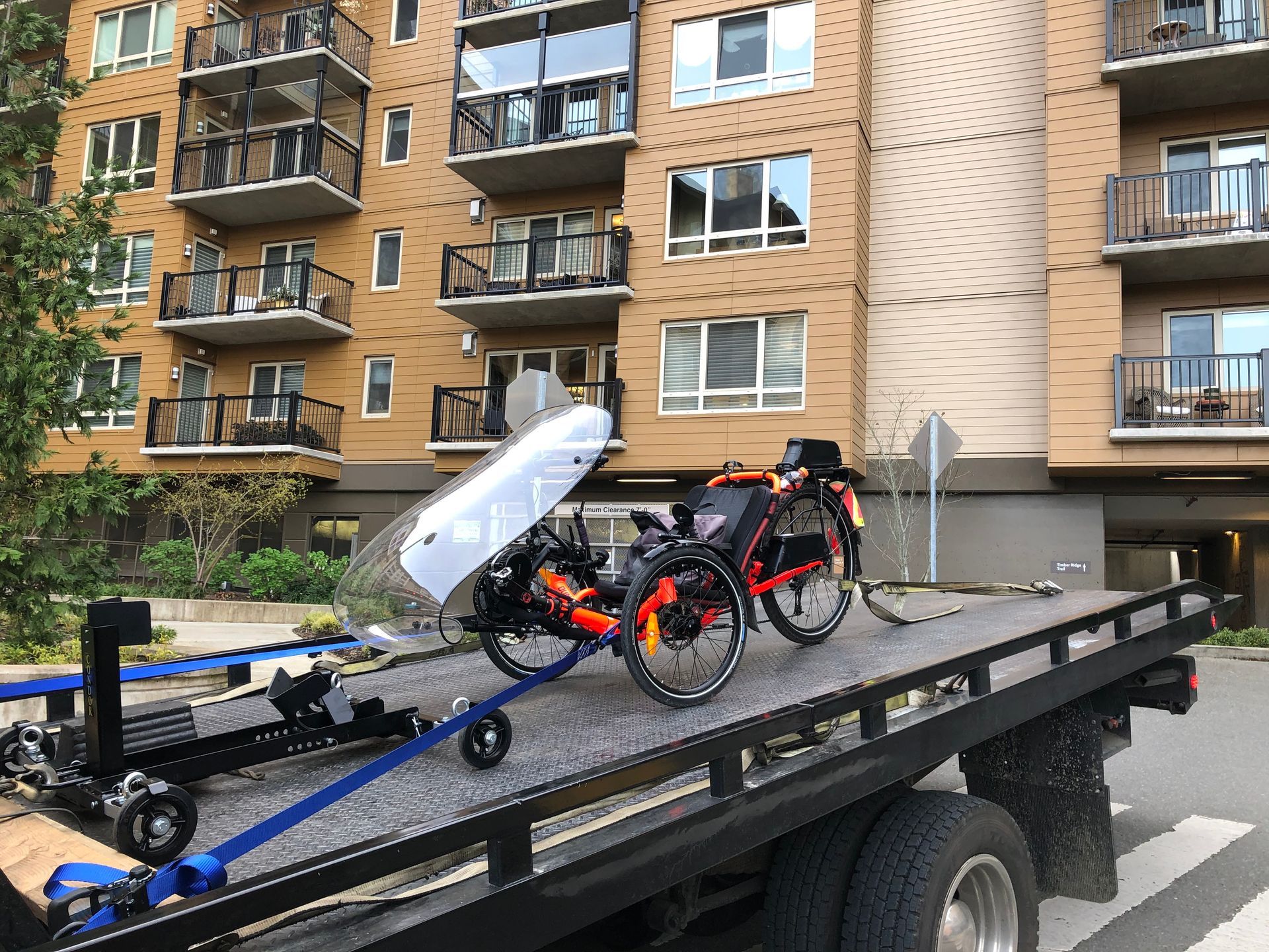 Two bicycles are sitting on top of a tow truck in front of a building.