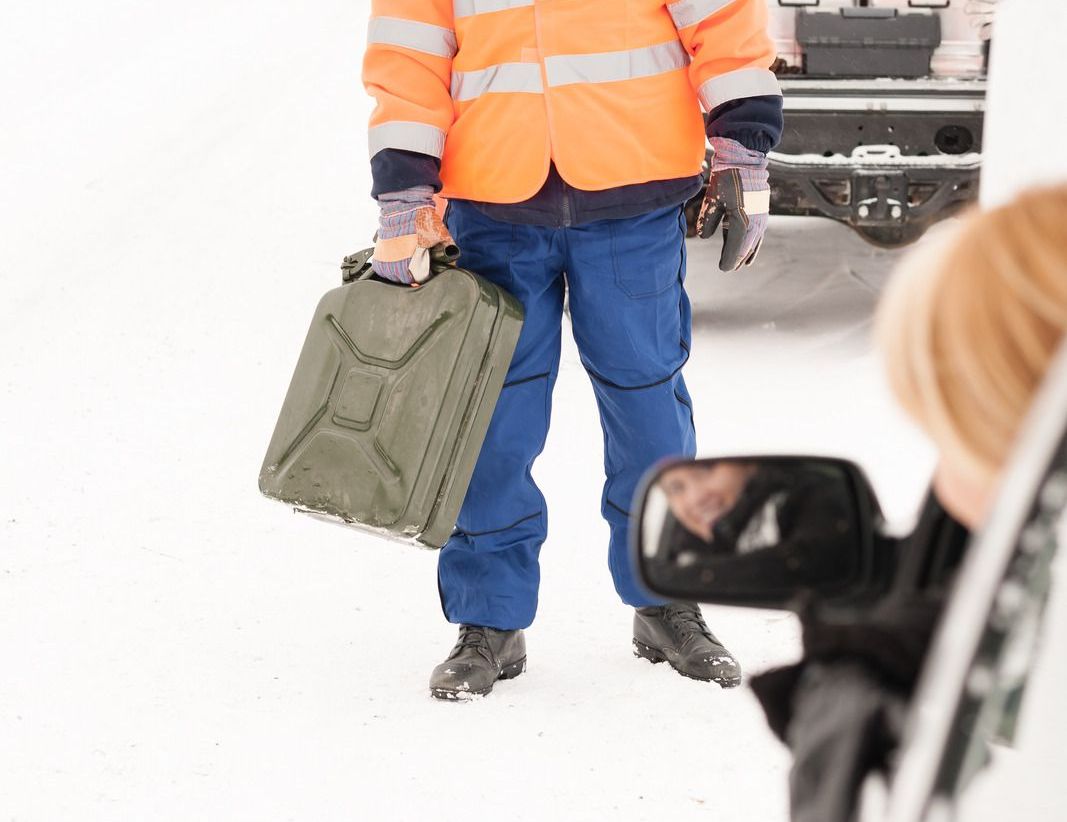 A man in an orange jacket is holding a green jerry can