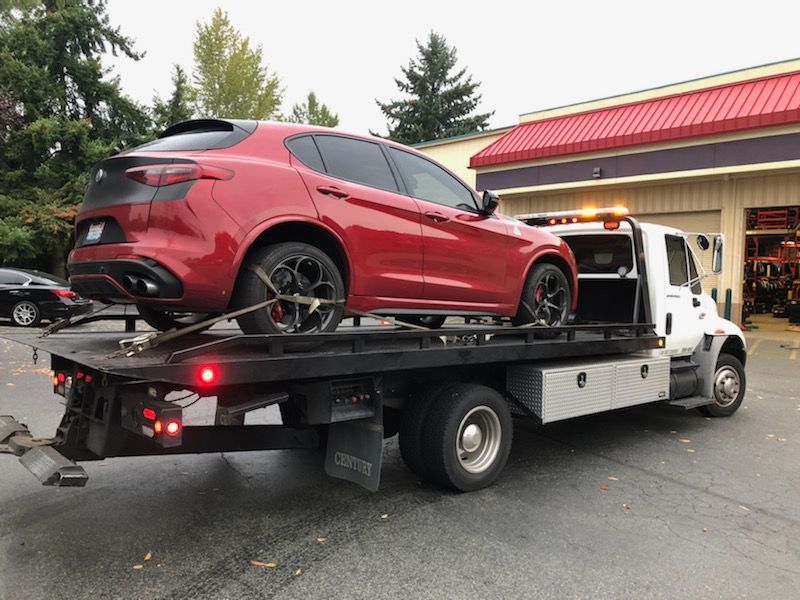 A red car is being towed by a tow truck.